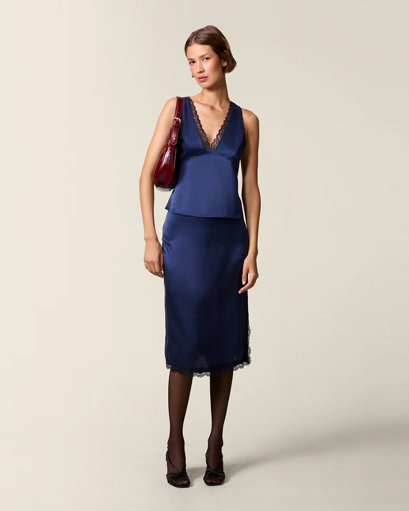 Elegancki, satynowy top na szerokich ramiączkach Opal Rouje z głębokim, trójkątnym dekoltem obszytym zmysłową koronką. Odcięta pod biustem. Z tyłu, przy szyi zapinana na guzik. Na plecach posiada niewielkie rozcięcie i zapięcie na zamek błyskawiczny. Wykonana ze śliskiej tkaniny z jedwabiem.