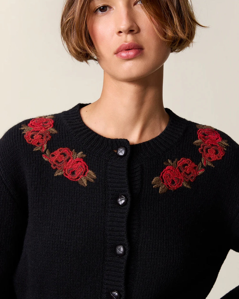 Czarny kardigan z efektownymi, haftowanymi kwiatami Atlas Rouje. Posiada okrągły dekolt, długie rękawy, dwie, przednie kieszenie i wcięcie w talii. Zapinany na guziki.