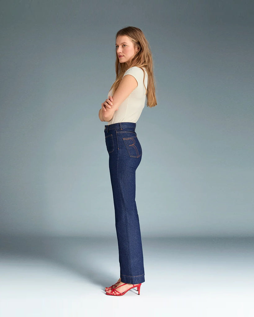 Granatowe jeansy o kobiecym fasonie Belleville Rouje z wysokim stanem i lekko rozszerzaną u dołu nogawką. Dopasowane w biodrach i udach. Z przodu posiadają naszyte, prostokątne kieszenie. Zapinane na zamek błyskawiczny i guzik. Obszyte kontrastową, rudą nicią