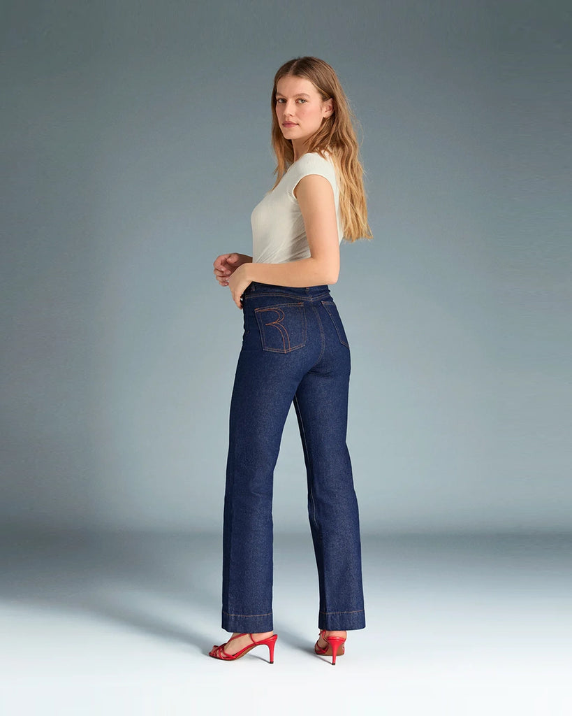 Granatowe jeansy o kobiecym fasonie Belleville Rouje z wysokim stanem i lekko rozszerzaną u dołu nogawką. Dopasowane w biodrach i udach. Z przodu posiadają naszyte, prostokątne kieszenie. Zapinane na zamek błyskawiczny i guzik. Obszyte kontrastową, rudą nicią