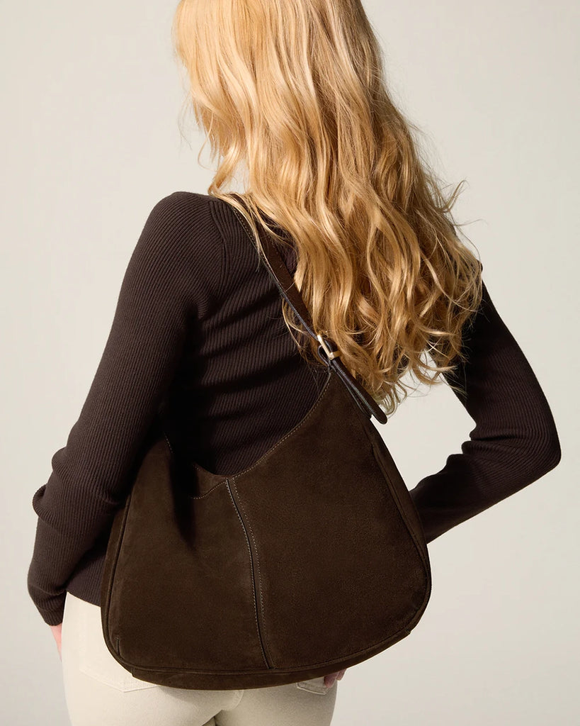 Zamszowa, brązowa torebka o średniej wielkości Big Rouje z zaokrąglonymi kątami i krótkim, regulowanym paskiem do wygodnego trzymania w dłoni i zawieszenia na ramieniu. Zapinana za pomocą magnesu. Wewnątrz obszyta różową, satynową podszewką.