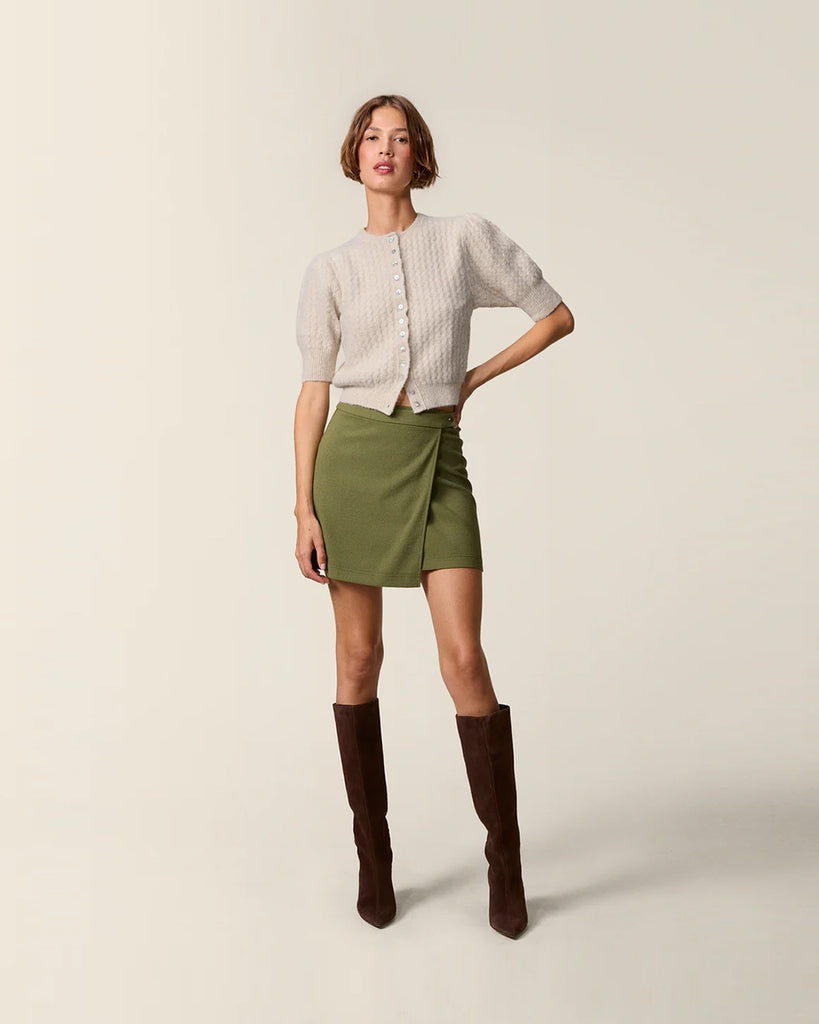 Krótki kardigan z bufiastymi rękawami przed łokieć Cassia Rouje. Posiada okrągły dekolt. Zapinany na drobne guziki z masy perłowej. Sweter ma prosty krój i jest wykończony ściągaczami.