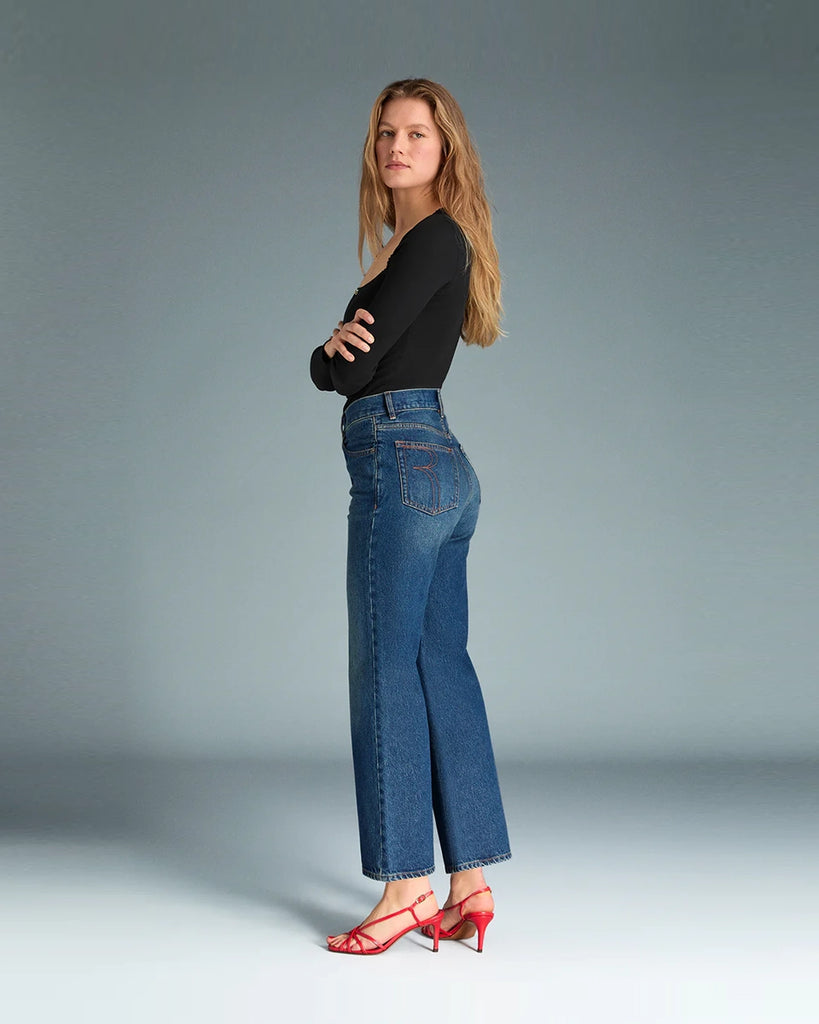 Granatowe jeansy o kobiecym fasonie Concorde Rouje z wysokim stanem i rozszerzaną u dołu, skróconą nogawką. Dopasowane w biodrach i udach. Posiadają pięć kieszeni. Nad lewą kieszenią znajduje się niewielka, haftowana litera R. Zapinane na zamek błyskawiczny i guzik. To model pięknie podkreślający sylwetkę. 