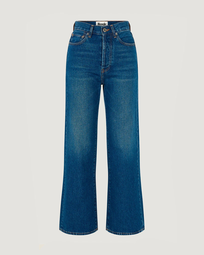 Granatowe jeansy o kobiecym fasonie Concorde Rouje z wysokim stanem i rozszerzaną u dołu, skróconą nogawką. Dopasowane w biodrach i udach. Posiadają pięć kieszeni. Nad lewą kieszenią znajduje się niewielka, haftowana litera R. Zapinane na zamek błyskawiczny i guzik. To model pięknie podkreślający sylwetkę. 