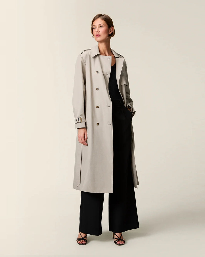 Klasyczny luźny, dwurzędowy prochowiec Ezra Rouje wiązany w talii za pomocą wyciąganego, szerokiego paska. Posiada kołnierzyk, pagony na ramionach i luźne rękawy z paskami przy mankietach. Z tyłu u dołu ma rozcięcie. Płaszcz posiada dwie, boczne kieszenie i podszewkę we wzór w panterę. Jest zapinany na guziki imitujące poroże.