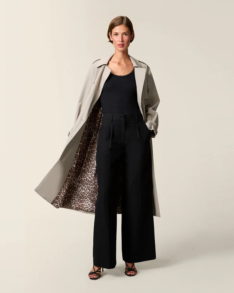 Klasyczny luźny, dwurzędowy prochowiec Ezra Rouje wiązany w talii za pomocą wyciąganego, szerokiego paska. Posiada kołnierzyk, pagony na ramionach i luźne rękawy z paskami przy mankietach. Z tyłu u dołu ma rozcięcie. Płaszcz posiada dwie, boczne kieszenie i podszewkę we wzór w panterę. Jest zapinany na guziki imitujące poroże.