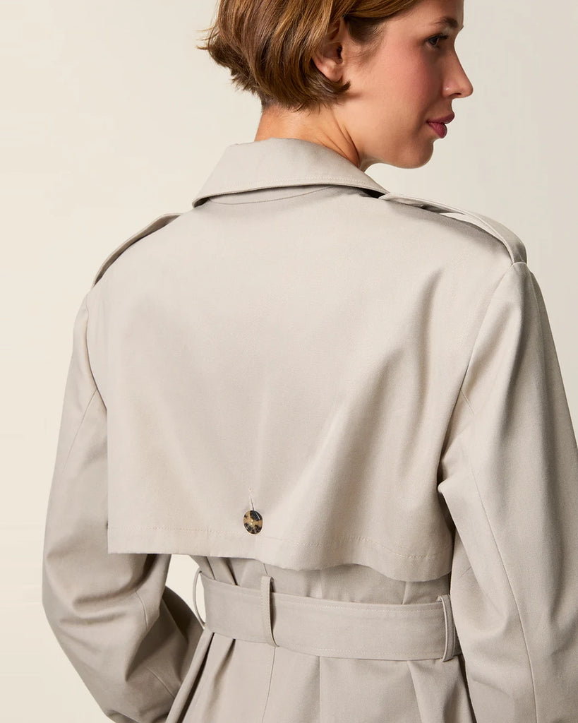 Klasyczny luźny, dwurzędowy prochowiec Ezra Rouje wiązany w talii za pomocą wyciąganego, szerokiego paska. Posiada kołnierzyk, pagony na ramionach i luźne rękawy z paskami przy mankietach. Z tyłu u dołu ma rozcięcie. Płaszcz posiada dwie, boczne kieszenie i podszewkę we wzór w panterę. Jest zapinany na guziki imitujące poroże.