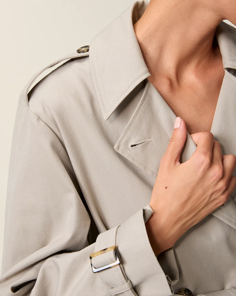 Klasyczny luźny, dwurzędowy prochowiec Ezra Rouje wiązany w talii za pomocą wyciąganego, szerokiego paska. Posiada kołnierzyk, pagony na ramionach i luźne rękawy z paskami przy mankietach. Z tyłu u dołu ma rozcięcie. Płaszcz posiada dwie, boczne kieszenie i podszewkę we wzór w panterę. Jest zapinany na guziki imitujące poroże.