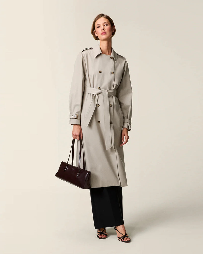 Klasyczny luźny, dwurzędowy prochowiec Ezra Rouje wiązany w talii za pomocą wyciąganego, szerokiego paska. Posiada kołnierzyk, pagony na ramionach i luźne rękawy z paskami przy mankietach. Z tyłu u dołu ma rozcięcie. Płaszcz posiada dwie, boczne kieszenie i podszewkę we wzór w panterę. Jest zapinany na guziki imitujące poroże.