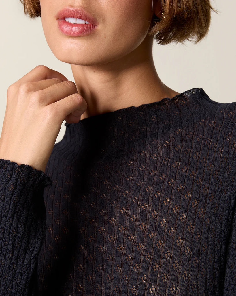 Cienki, ażurowy, dzianinowy longsleeve Galina Rouje o dopasowanym fasonie. Posiada wysoki dekolt. Przy szyi i na końcu rękawów wykończony falbanką. Idealny do spodnie z wysokim stanem.