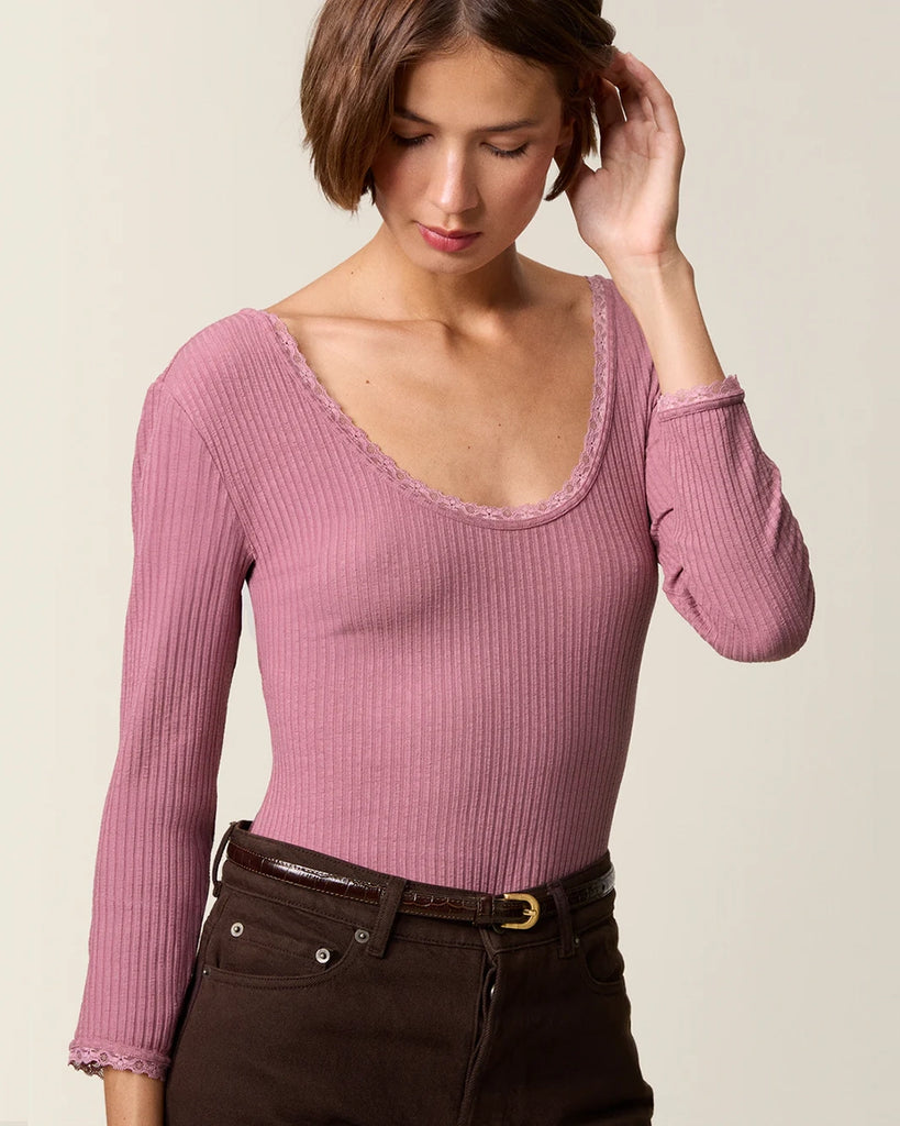 Dopasowana, prosta bluzka Gio Rouje z głębokim, okrągłym dekoltem obszytym uroczą koronką. Posiada wąskie rękawy o długości przed nadgarstki wykończone koronką. Wykonana z cienkiej tkaniny z prążkowaną fakturą.