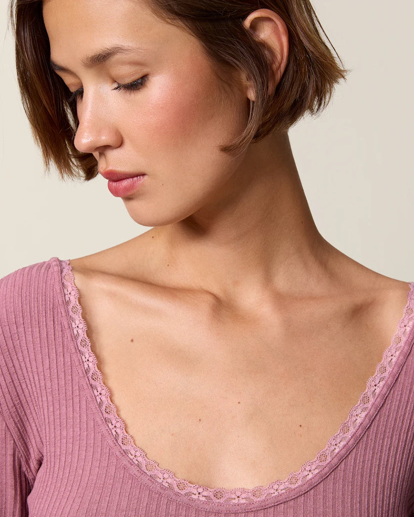 Dopasowana, prosta bluzka Gio Rouje z głębokim, okrągłym dekoltem obszytym uroczą koronką. Posiada wąskie rękawy o długości przed nadgarstki wykończone koronką. Wykonana z cienkiej tkaniny z prążkowaną fakturą.