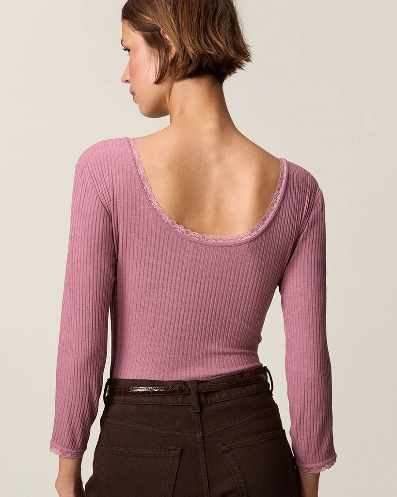 Dopasowana, prosta bluzka Gio Rouje z głębokim, okrągłym dekoltem obszytym uroczą koronką. Posiada wąskie rękawy o długości przed nadgarstki wykończone koronką. Wykonana z cienkiej tkaniny z prążkowaną fakturą.