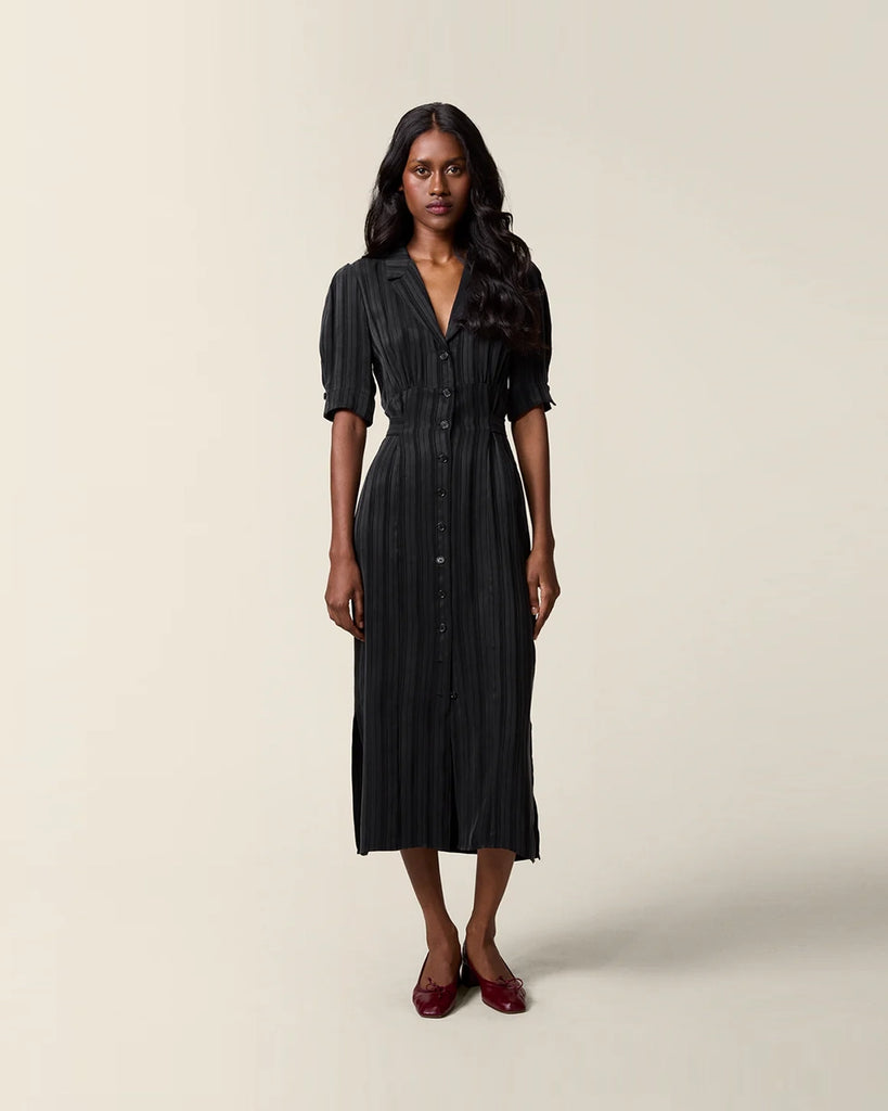 Czarna sukienka midi w paski Laureline Rouje z krótkimi, bufiastymi rękawami, trójkątnym dekoltem i kołnierzykiem. Zapinana na guziki. Dopasowana i wiązana z tyłu w talii za pomocą paska. Sukienka ma długość do połowy łydki.