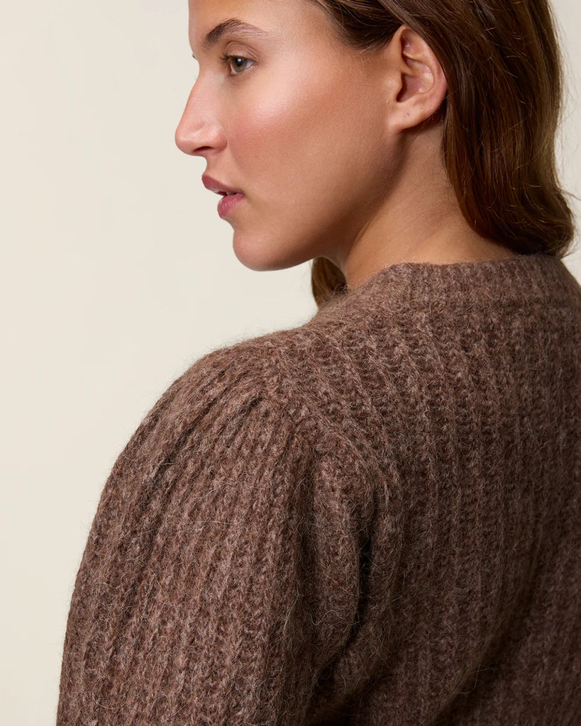 Ciepły, brązowy kardigan Lisia Rouje z okrągłym dekoltem i luźnymi, długimi rękawami. Zwężany i dopasowany w talii. Zapinany na guziki. Wykonany z grubej dzianiny z wełną i kaszmirem z prążkowaną fakturą.