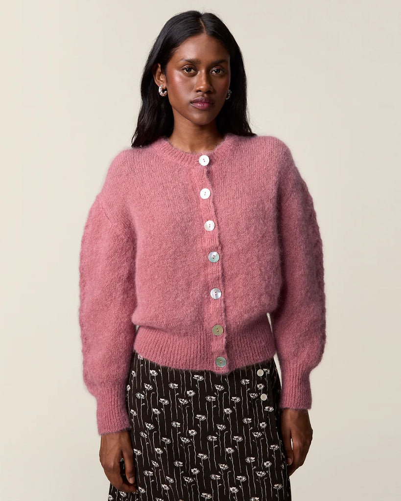 Luźny, moherowy kardigan Maina Rouje z okrągłym dekoltem i balonowymi, reglanowymi rękawami z ażurowym wzorem na bokach. Zapinany na duże guziki z masy perłowej. Posiada prosty krój. Jest wykończony ściągaczami