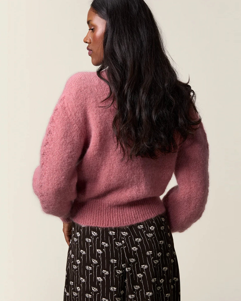 Luźny, moherowy kardigan Maina Rouje z okrągłym dekoltem i balonowymi, reglanowymi rękawami z ażurowym wzorem na bokach. Zapinany na duże guziki z masy perłowej. Posiada prosty krój. Jest wykończony ściągaczami