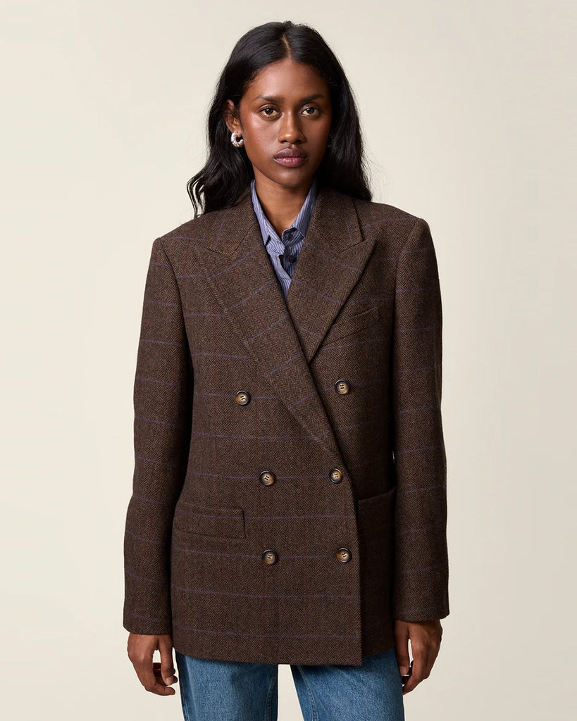 Klasyczna, dwurzędowa marynarka w kratkę z wełną Marcel Rouje. Posiada prosty krój, dekolt w kształcie litery V i klapy. Marynarka ma dwie, przednie kieszenie i rozcięcie z tyłu oraz podszewkę. Zapinana na guziki imitujące poroże.