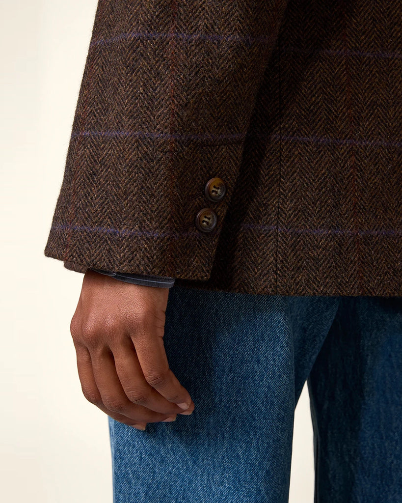 Klasyczna, dwurzędowa marynarka w kratkę z wełną Marcel Rouje. Posiada prosty krój, dekolt w kształcie litery V i klapy. Marynarka ma dwie, przednie kieszenie i rozcięcie z tyłu oraz podszewkę. Zapinana na guziki imitujące poroże.