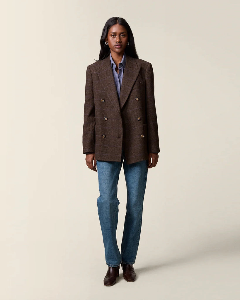 Klasyczna, dwurzędowa marynarka w kratkę z wełną Marcel Rouje. Posiada prosty krój, dekolt w kształcie litery V i klapy. Marynarka ma dwie, przednie kieszenie i rozcięcie z tyłu oraz podszewkę. Zapinana na guziki imitujące poroże.