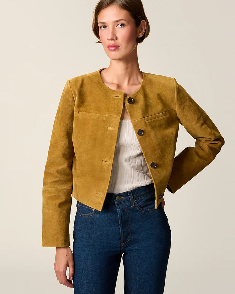 Krótka, zamszowa kurtka o pudełkowym fasonie Milo Rouje z okrągłym dekoltem. Zapinana na duże, szylkretowe guziki. Posiada dwie kieszenie nad piersiami.