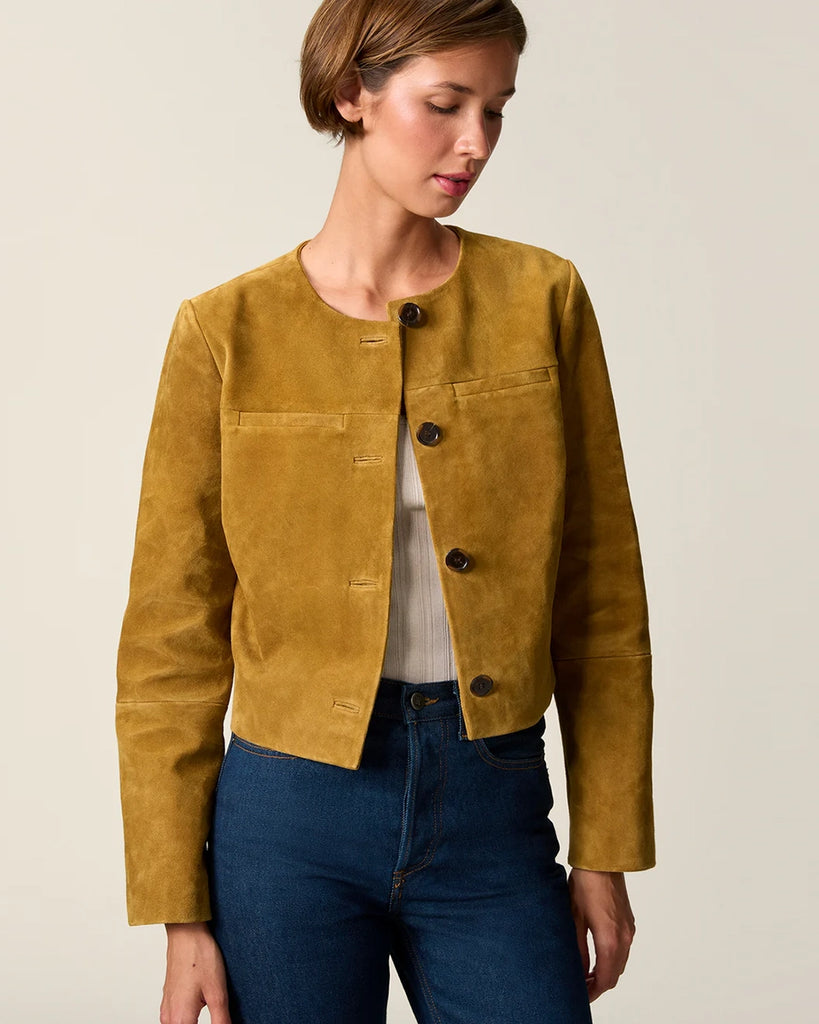 Krótka, zamszowa kurtka o pudełkowym fasonie Milo Rouje z okrągłym dekoltem. Zapinana na duże, szylkretowe guziki. Posiada dwie kieszenie nad piersiami.