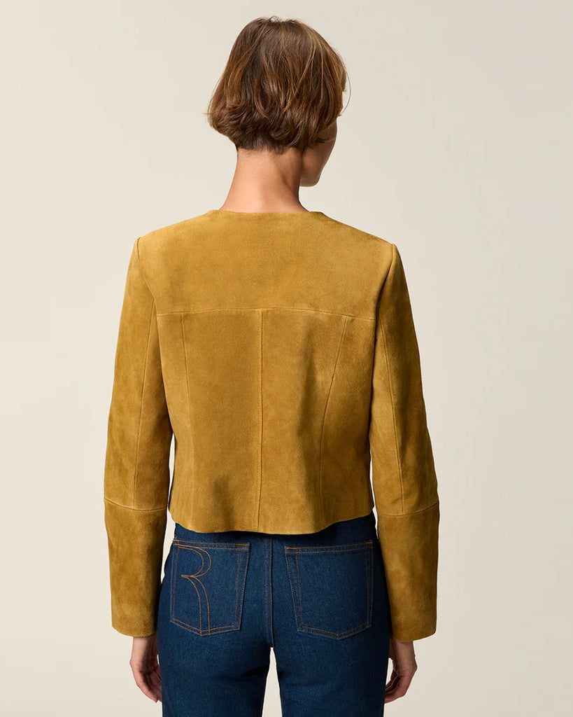 Krótka, zamszowa kurtka o pudełkowym fasonie Milo Rouje z okrągłym dekoltem. Zapinana na duże, szylkretowe guziki. Posiada dwie kieszenie nad piersiami.