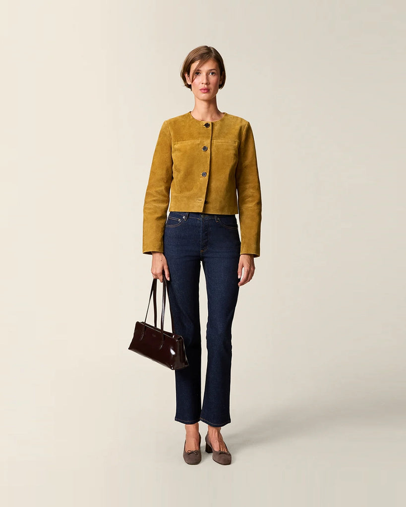 Krótka, zamszowa kurtka o pudełkowym fasonie Milo Rouje z okrągłym dekoltem. Zapinana na duże, szylkretowe guziki. Posiada dwie kieszenie nad piersiami.