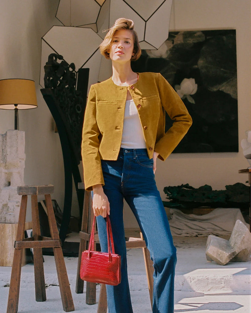 Krótka, zamszowa kurtka o pudełkowym fasonie Milo Rouje z okrągłym dekoltem. Zapinana na duże, szylkretowe guziki. Posiada dwie kieszenie nad piersiami.