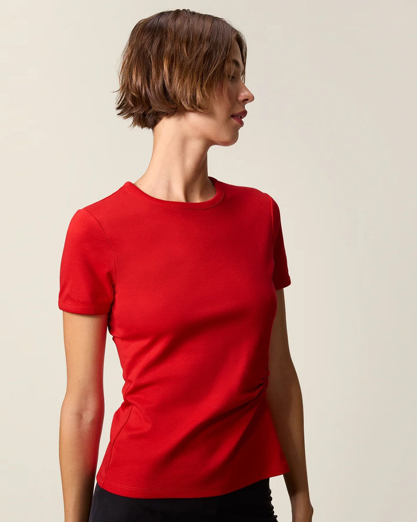 Czerwony, bawełniany t-shirt Nemi Rouje z okrągłym dekoltem i wąskim, krótkim rękawem. Po lewej stronie, w talii posiada ciekawe marszczenie i haftowaną literę R.
