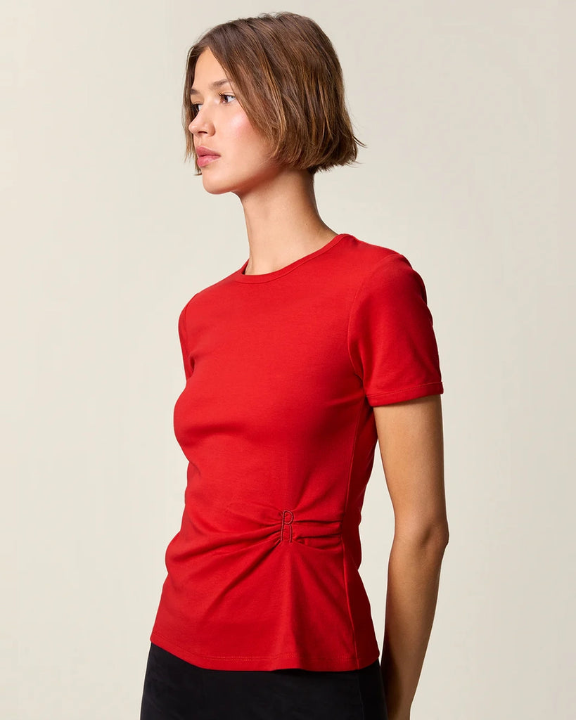 Czerwony, bawełniany t-shirt Nemi Rouje z okrągłym dekoltem i wąskim, krótkim rękawem. Po lewej stronie, w talii posiada ciekawe marszczenie i haftowaną literę R.