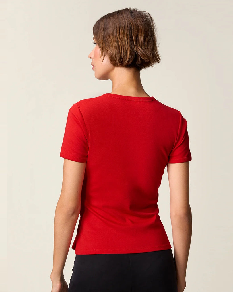 Czerwony, bawełniany t-shirt Nemi Rouje z okrągłym dekoltem i wąskim, krótkim rękawem. Po lewej stronie, w talii posiada ciekawe marszczenie i haftowaną literę R.