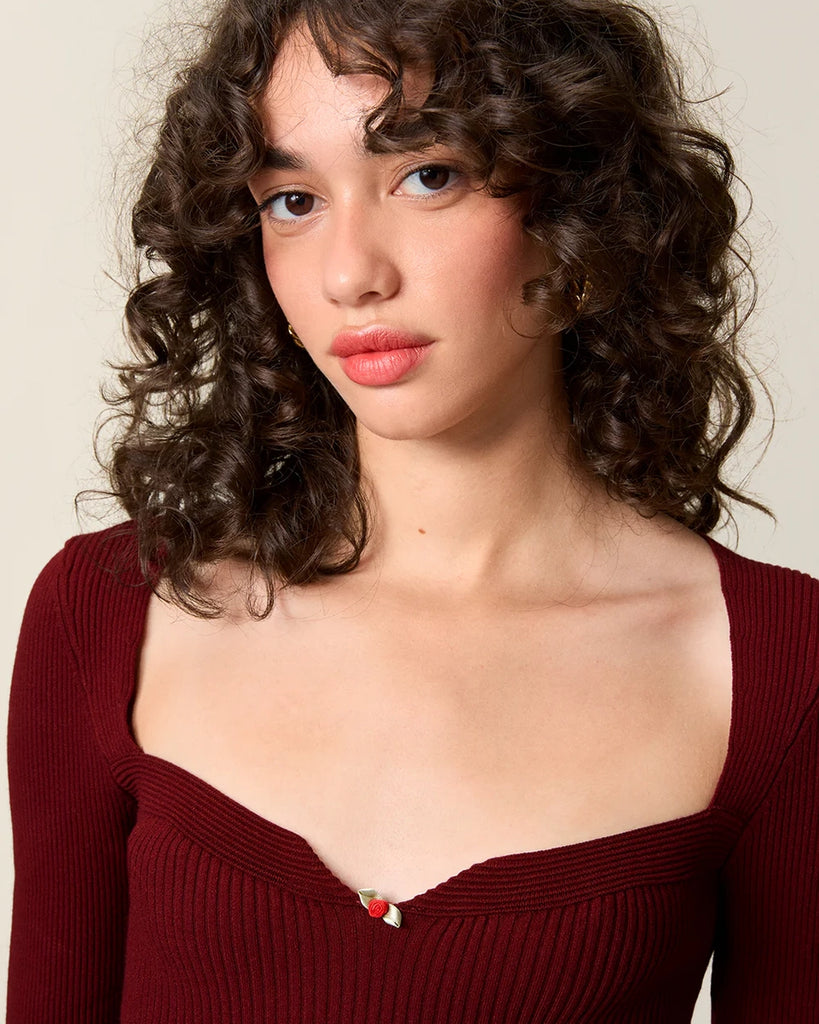 Dzianinowa bluzka Nesta Rouje o dopasowanym fasonie pięknie podkreślającym sylwetkę. Posiada efektowny, sercowy dekolt z niewielką, uroczą różyczką przy piersiach oraz wąskie rękawy 3/4.