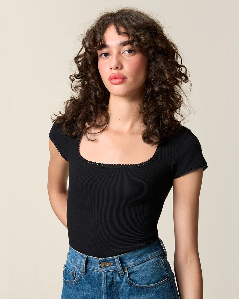 Dopasowany, czarny t-shirt Siam Rouje z głębokim okrągłym dekoltem i krótkim rękawem. Wykończony delikatną koronką. Wykonany z lekko elastycznej, bawełnianej tkaniny o prążkowanej fakturze. 