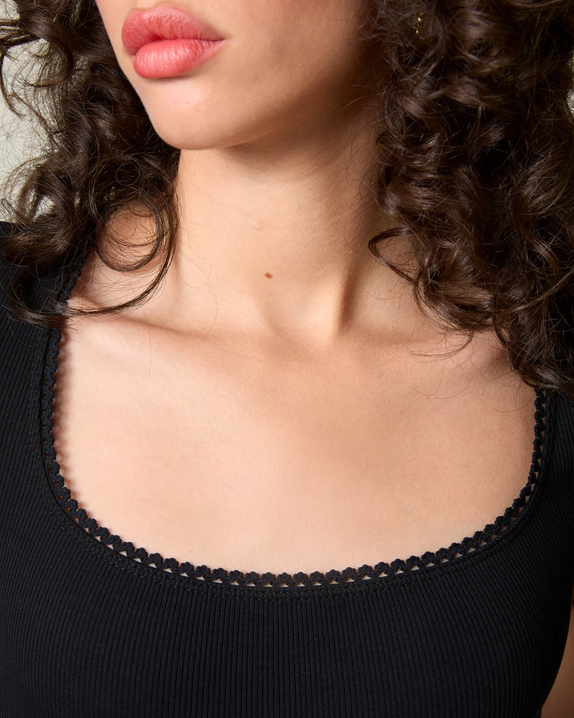 Dopasowany, czarny t-shirt Siam Rouje z głębokim okrągłym dekoltem i krótkim rękawem. Wykończony delikatną koronką. Wykonany z lekko elastycznej, bawełnianej tkaniny o prążkowanej fakturze. 