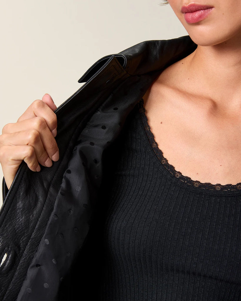 Czarna, krótka kurtka skórzana Stan Rouje o prostym kroju. Posiada kołnierzyk i dwie, boczne kieszenie. Z przodu i przy mankietach rękawów zapinana na guziki. Kurtka ma podszewkę we wzór w grochy.