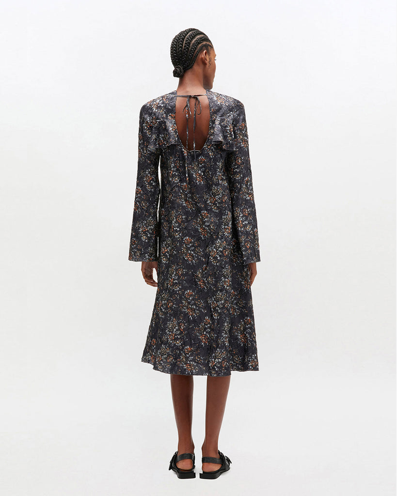 Prosta, midi sukienka 0982 GANNI Shibori Black z okrągłym dekoltem i długimi rękawami. Posiada falbankę na dekolcie i romantyczny, kwiatowy wzór. Wykończona jest plisowanym materiałem shibori. Ma długość za kolano. Idealna na codzień.