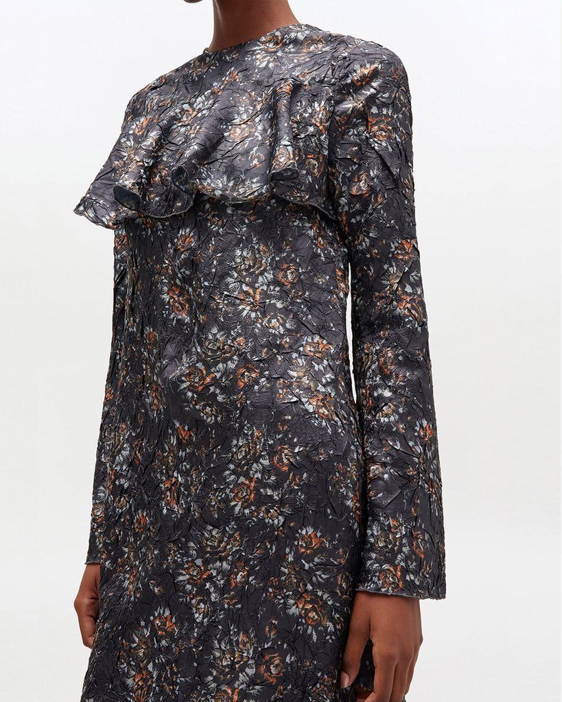 Prosta, midi sukienka 0982 GANNI Shibori Black z okrągłym dekoltem i długimi rękawami. Posiada falbankę na dekolcie i romantyczny, kwiatowy wzór. Wykończona jest plisowanym materiałem shibori. Ma długość za kolano. Idealna na codzień.