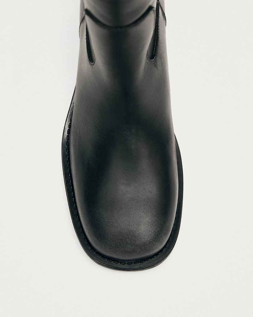 Czarne, masywne kozaki typu oficerki ALOHAS Sajan Black Leather z efektem przetarcia. Wzorowane na tradycyjnych oficerkach z zaokrąglonymi noskami i podwyższoną, gumową podeszwą. Sięgają do łydki. Po bokach posiadają uchwyty z logo marki, które ułatwiają zakładanie. Wykonane z przetarcia czarnej skóry.&nbsp;