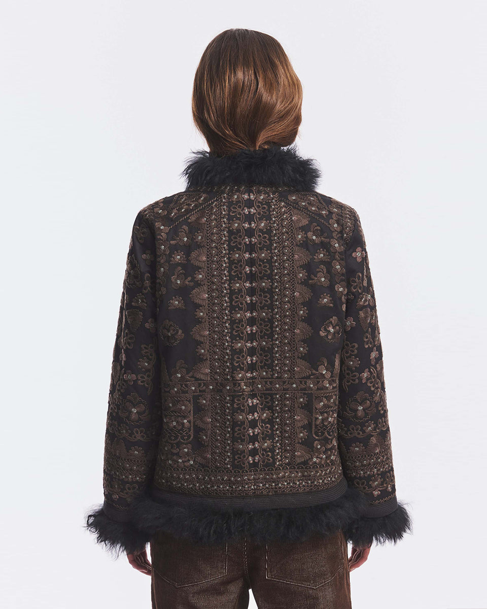 Obszerna kurtka średniej długości Sando Black Antik Batik zdobiona haftem inspirowanym motywami afgańskimi. Posiada długie rękawy, stójkę, zapięcie na haftki oraz kieszenie z przodu. Ma ręcznie wykonane hafty na całej powierzchni. Krawędzie kurtki wokół zapięcia, dekoltu oraz mankiety są wykończone ciemnym futerkiem, nadającym jej zimowy, luksusowy charakter. Kurtka sięga mniej więcej do bioder.&nbsp;

-Ozdobiona licznymi haftami

-Wykończona kontrastujacym futerkiem