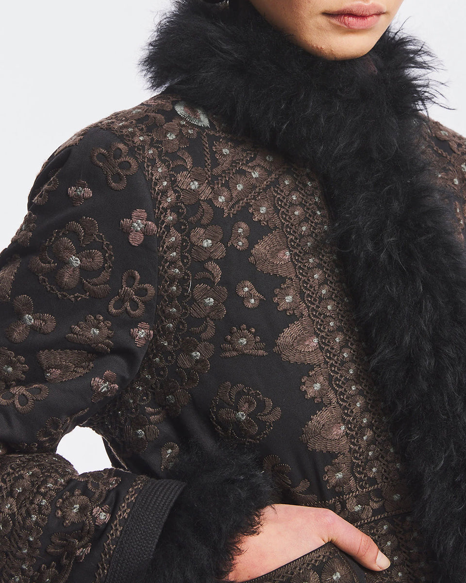 Obszerna kurtka średniej długości Sando Black Antik Batik zdobiona haftem inspirowanym motywami afgańskimi. Posiada długie rękawy, stójkę, zapięcie na haftki oraz kieszenie z przodu. Ma ręcznie wykonane hafty na całej powierzchni. Krawędzie kurtki wokół zapięcia, dekoltu oraz mankiety są wykończone ciemnym futerkiem, nadającym jej zimowy, luksusowy charakter. Kurtka sięga mniej więcej do bioder.&nbsp;

-Ozdobiona licznymi haftami

-Wykończona kontrastujacym futerkiem