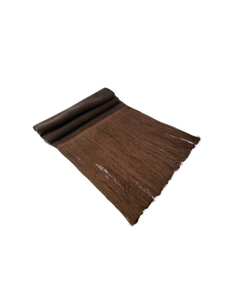 Obszerny szal Sciarpa Choco w kolorze brązowym wykonany w 100% z wełny. Zakończony jest długimi frędzlami w pasującym kolorze.
