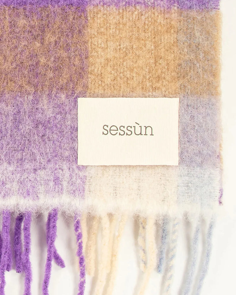 Ciepły, duży szalik Lucio francuskiej marki Sessun w wielokolorową kratę, z frędzlami na brzegach. W prawym dolnym rogu posiada haftowaną metkę z logo marki. Wykonany z miękkiej dzianiny z alpaką. Idealnie sprawdzi się do jesienno-zimowych stylizacji.