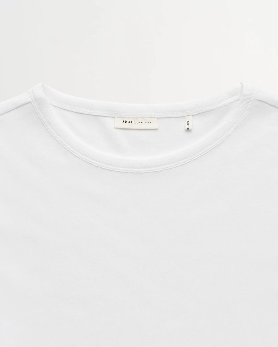 Minimalistyczny, biały, bawełniany longsleeve Seventies O-neck SKALL z okrągłym dekoltem i wąskimi, długimi rękawami. Posiada przylegający do ciała fason i delikatną, gładką fakturę. Wykonany z organicznej i bardzo przyjemnej dla skóry bawełny. To bluzka idealna do warstwowych stylizacji.&nbsp;

-Przylegający fason

-100% bawełna organiczna

-Zamów longsleeve w swoim normalnym rozmiarze