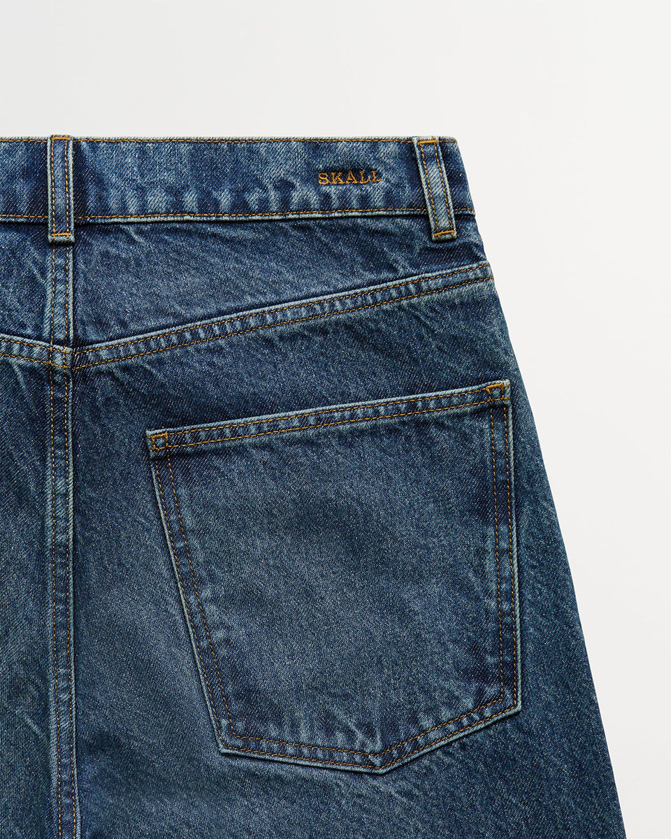Klasyczne jeansy Sharon Straight Washed Dark Blue marki SKALL z wysokim stanem, wąskimi, prostymi nogawkami i klasycznymi, jeansowymi detalami. Mają pięć kieszeni, szlufki na pasek oraz haftowane logo marki z tyłu w pasie. Wykonane w 100% z certyfikowanej bawełny organicznej.&nbsp;

-Wysoki stan

-Wąskie, proste nogawki

-100% bawełna organiczna