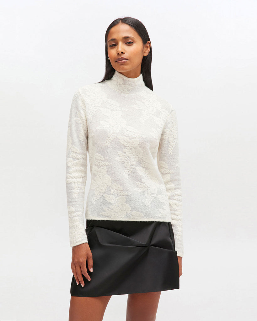 Lekko prześwitujący golf 2643 GANNI Egret z wysokim kołnierzykiem i długimi rękawami z kwiatowym printem. Posiada zapięcie na ozdobne guziczki z tyłu. Idealny do spódnicy lub luźnych spodni. Wykonany z tkaniny z alpaką i wełną.
