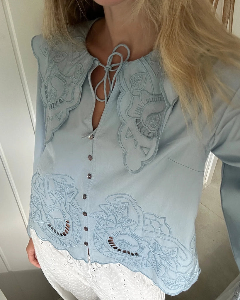 Romantyczna, koszulowa bluzka Cameron SISSEL EDELBO z dużym, efektownym kołnierzem i długim, rozszerzanym rękawem. Wiązana pod szyją. Zapinana na guziki z masy perłowej i haftki