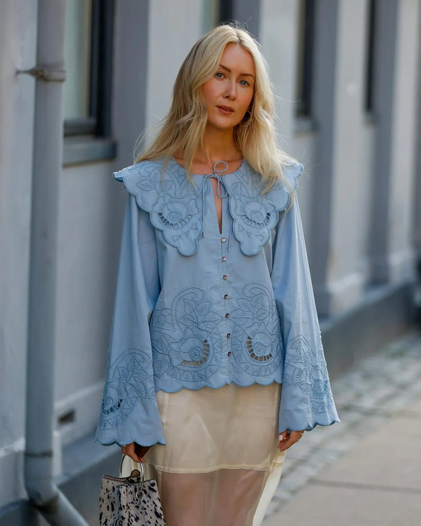 Romantyczna, koszulowa bluzka Cameron SISSEL EDELBO z dużym, efektownym kołnierzem i długim, rozszerzanym rękawem. Wiązana pod szyją. Zapinana na guziki z masy perłowej i haftki