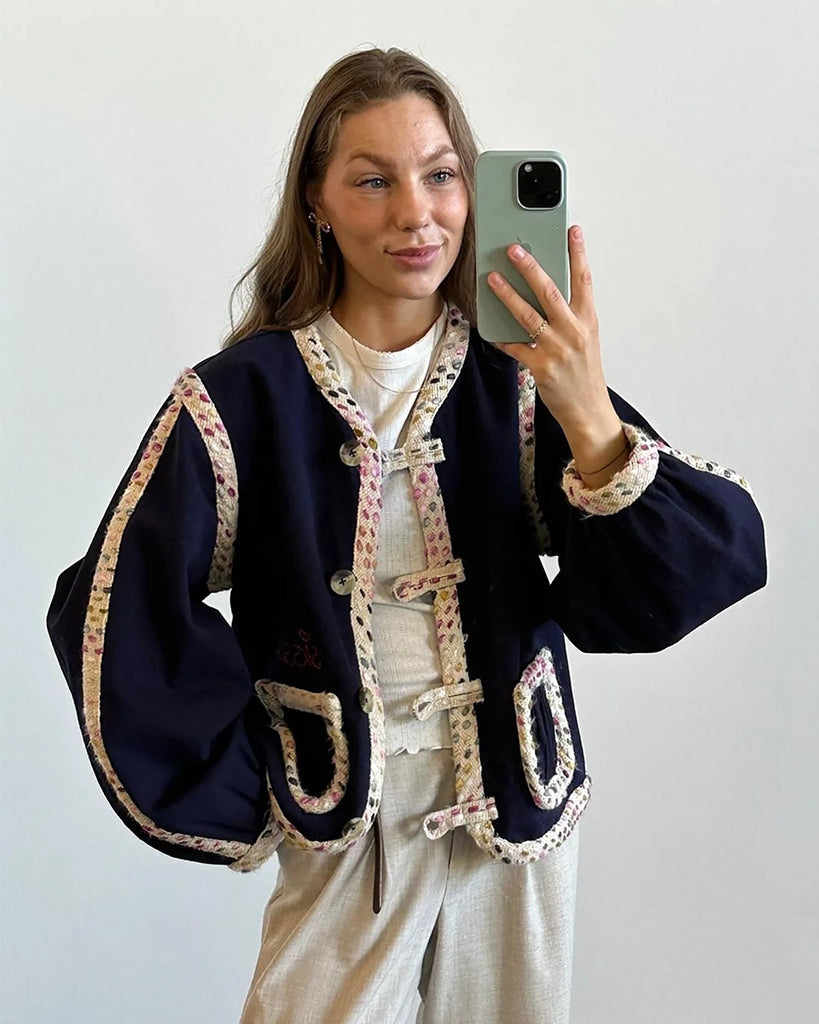 Cienka, krótka kurtka Como SISSEL EDELBO o pudełkowym kroju z długimi, balonowymi rękawami. Zapinana na duże guziki i haftki. Wykończona zaokrąglonymi rogami i grubą lamówką z tkaniny boucle