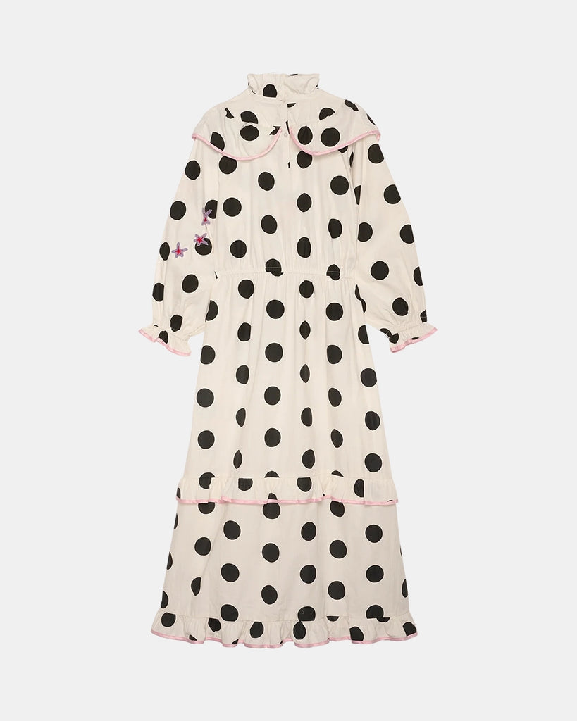 Bawełniana sukienka maxi w grochy Diana SISSEL EDELBO z długimi, balonowymi rękawami, wysokim kołnierzykiem i efektowną falbaną przy dekolcie. Zwężana i elastyczna w talii. U dołu i przy mankietach wykończona falbankami. Dekorowana uroczymi, kolorowymi haftami z motywami serc, kwiatów, gwiazd i księżyca. Obszyta różową lamówką. Sukienka ma długość do kostek